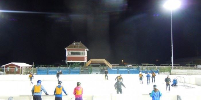 People ice skating on an outdoor ice rink.